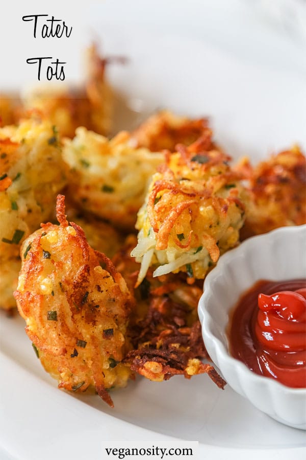 A Pinterest pin for cheesy vegan tater tots with a picture of a white platter of tots and a white scalloped dish with ketchup.