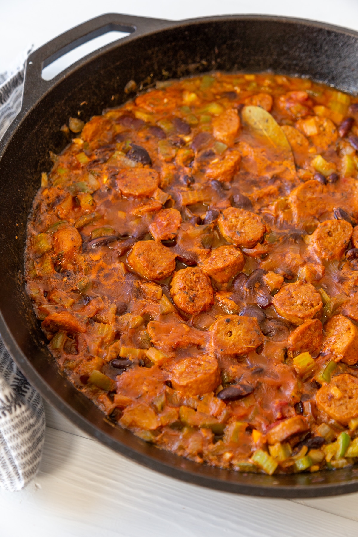 An iron skillet filled with spicy red beans and sausage. 