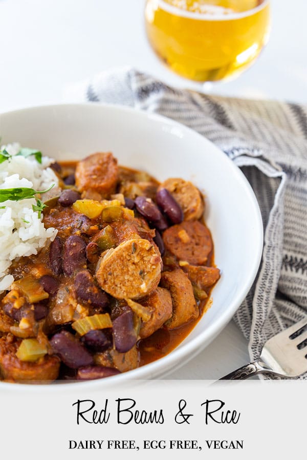A Pinterest pin for vegan red beans and rice with the beans and rice in a white bowl with a glass of beer in the background.