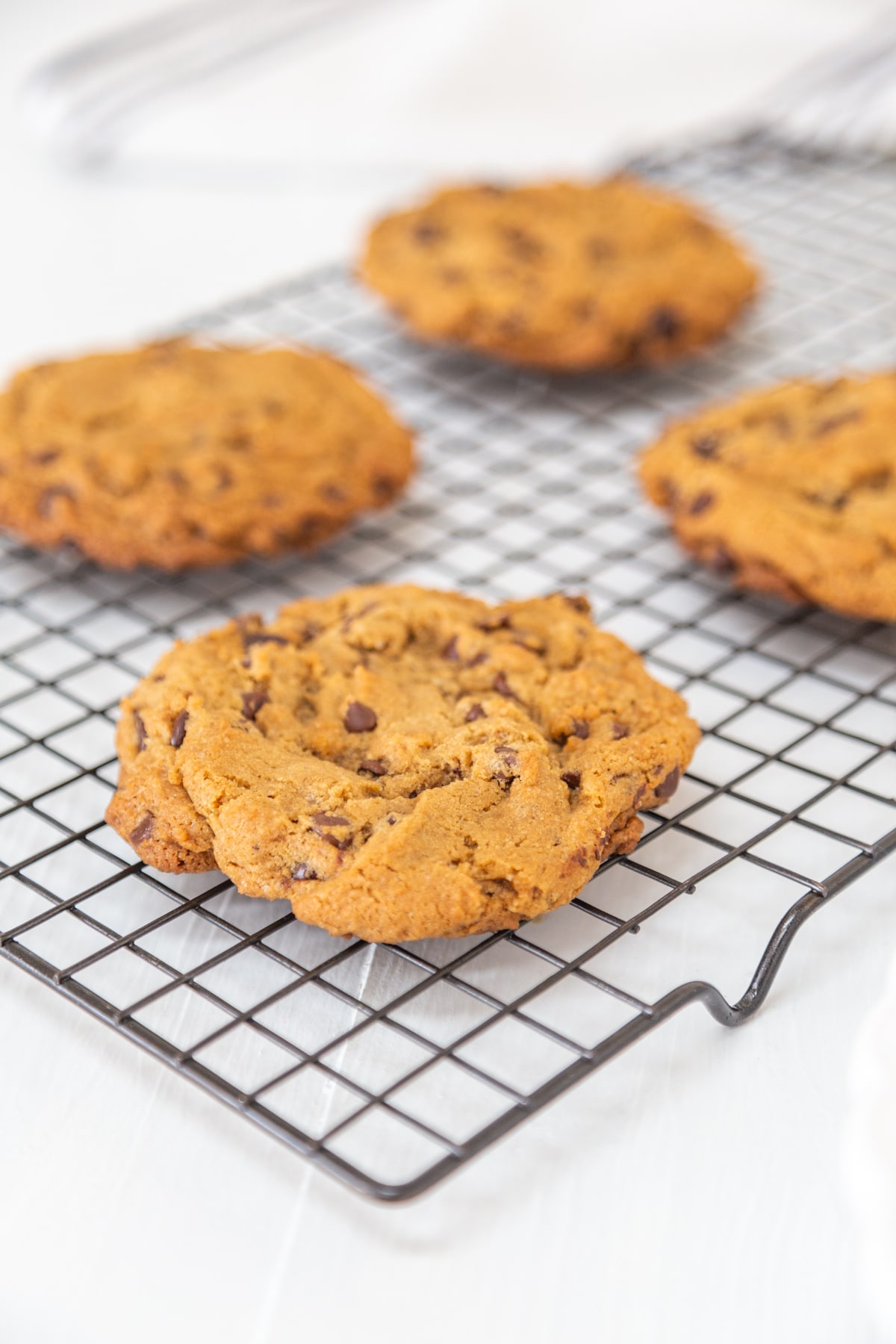 4 chocolate chip cookies on a wire cooling rack.