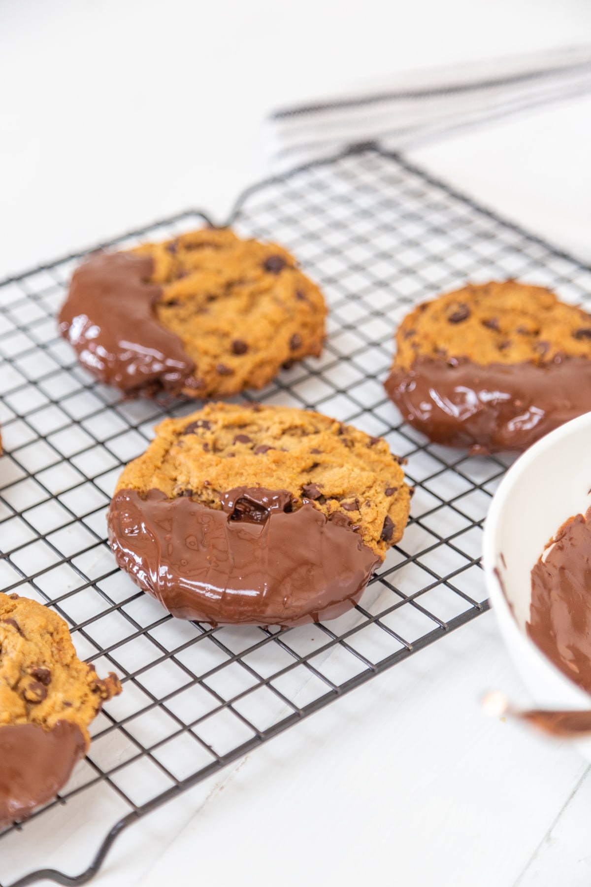 Chocolate dipped chocolate chip cookies on a wire cooling rack.