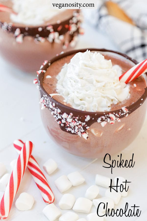 A Pinterest pin for spiked vegan peppermint hot chocolate with a picture of the hot chocolate in a glass mug with a chocolate & peppermint rimmed glass.